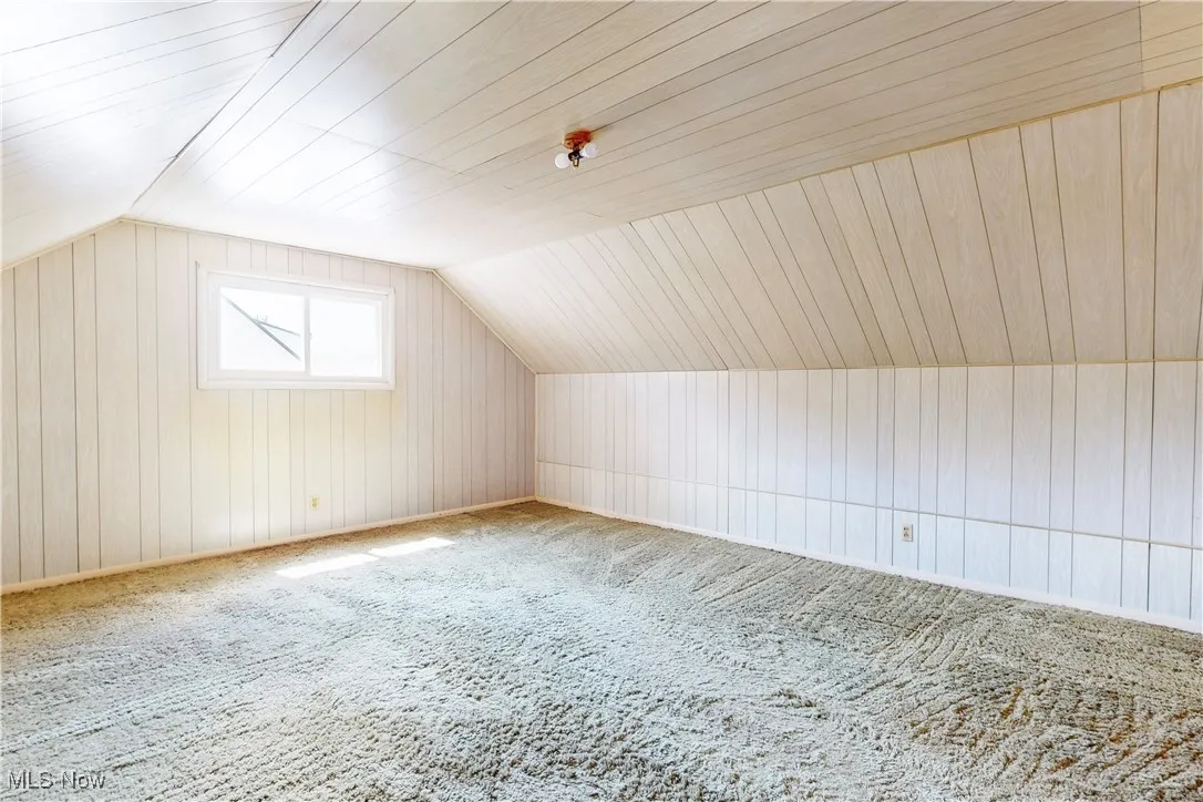 Bonus room with lofted ceiling, carpet floors, wood walls, and wood ceiling