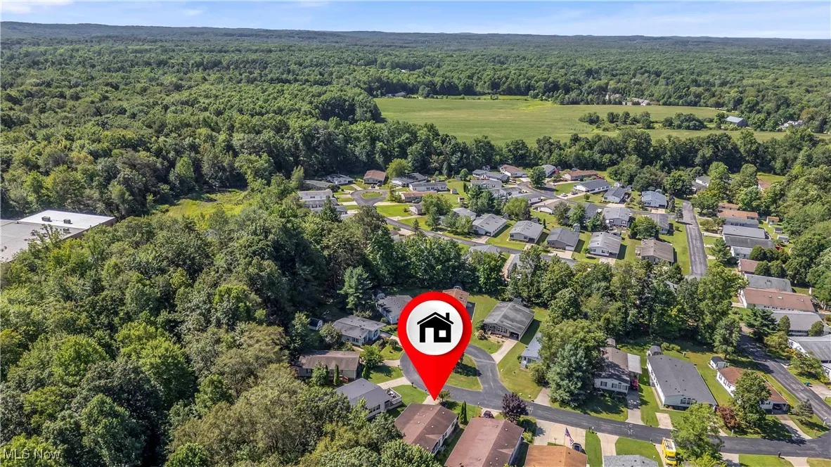Aerial view of property's location featuring nearby suburban area and a forest