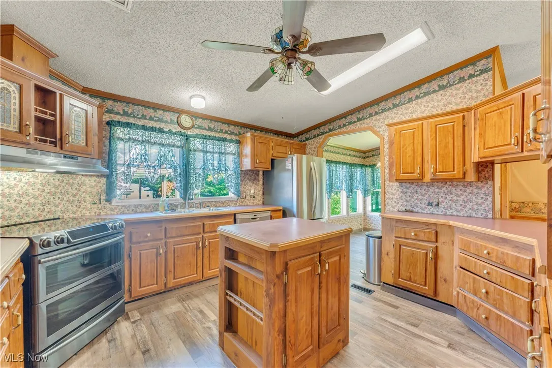 Kitchen with backsplash, open shelves, stainless steel appliances, arched walkways, and light wood finished floors