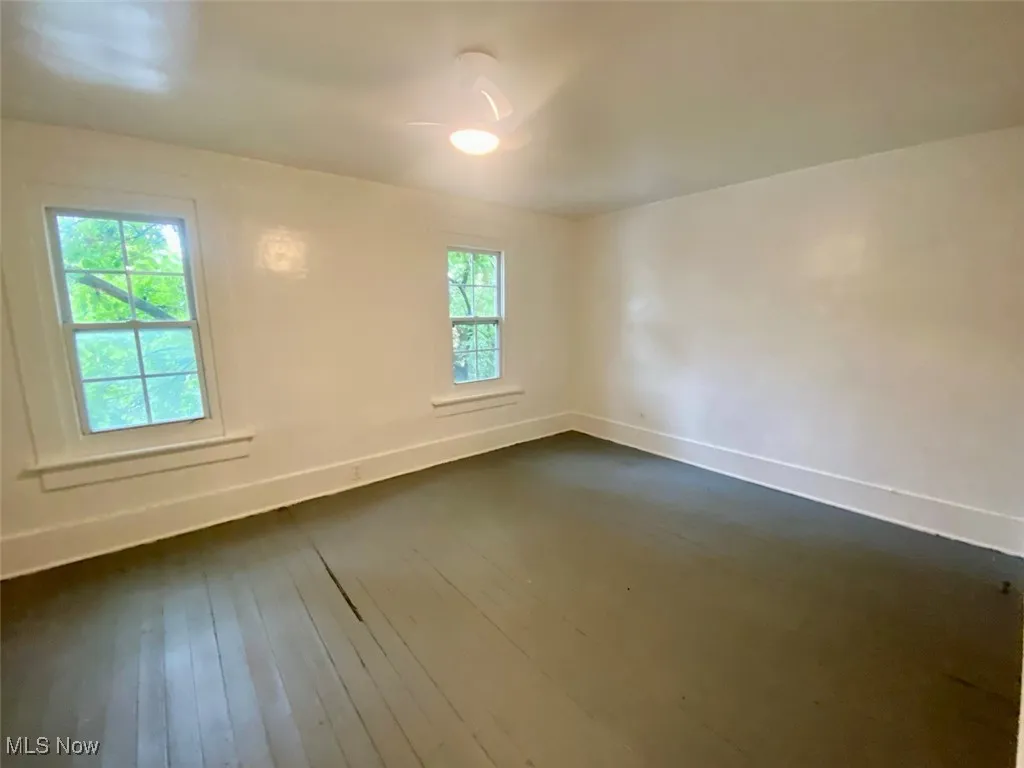 Empty room featuring baseboards and dark wood-style floors