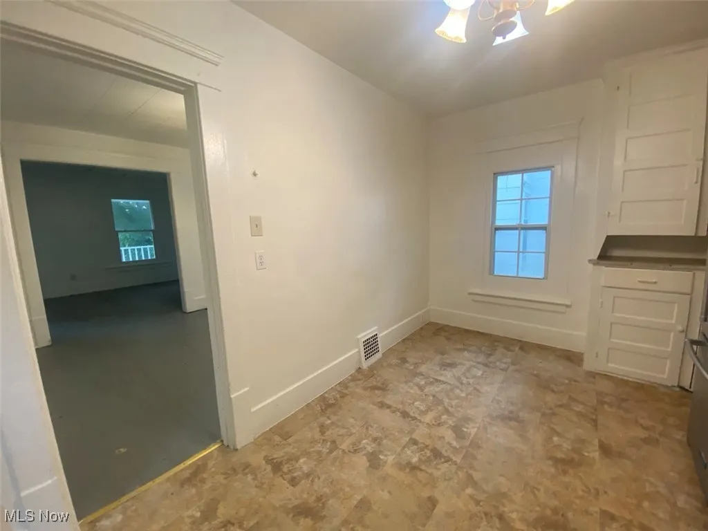 Unfurnished dining area featuring a chandelier and baseboards