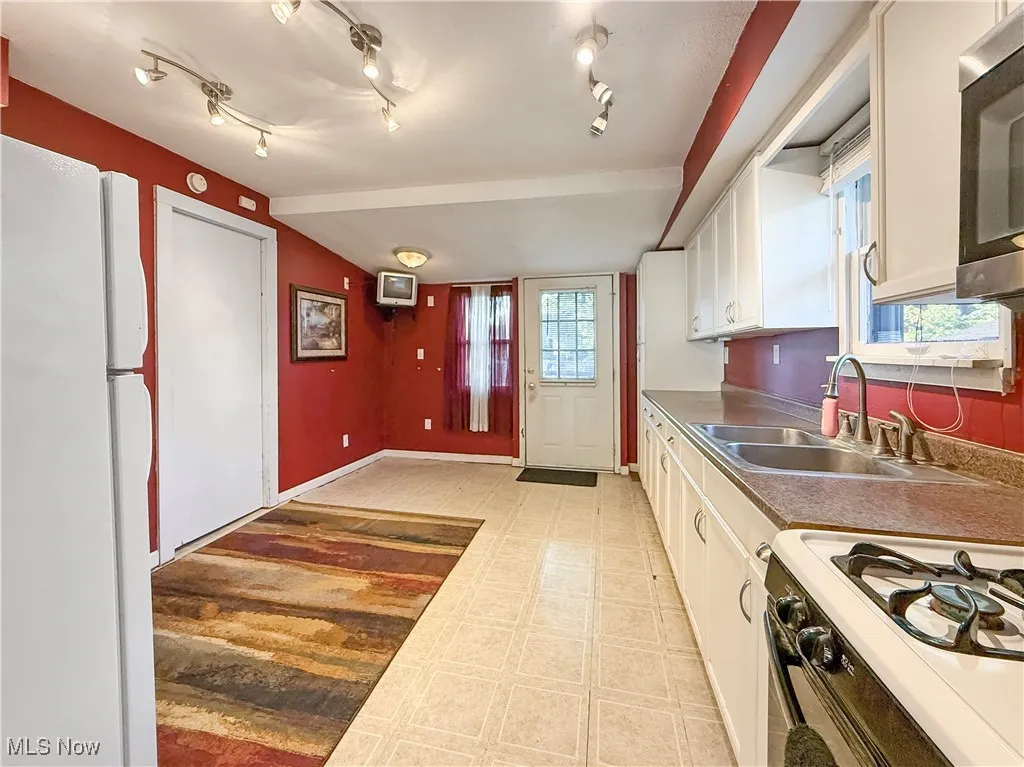 Kitchen with light floors, white appliances, and white cabinets