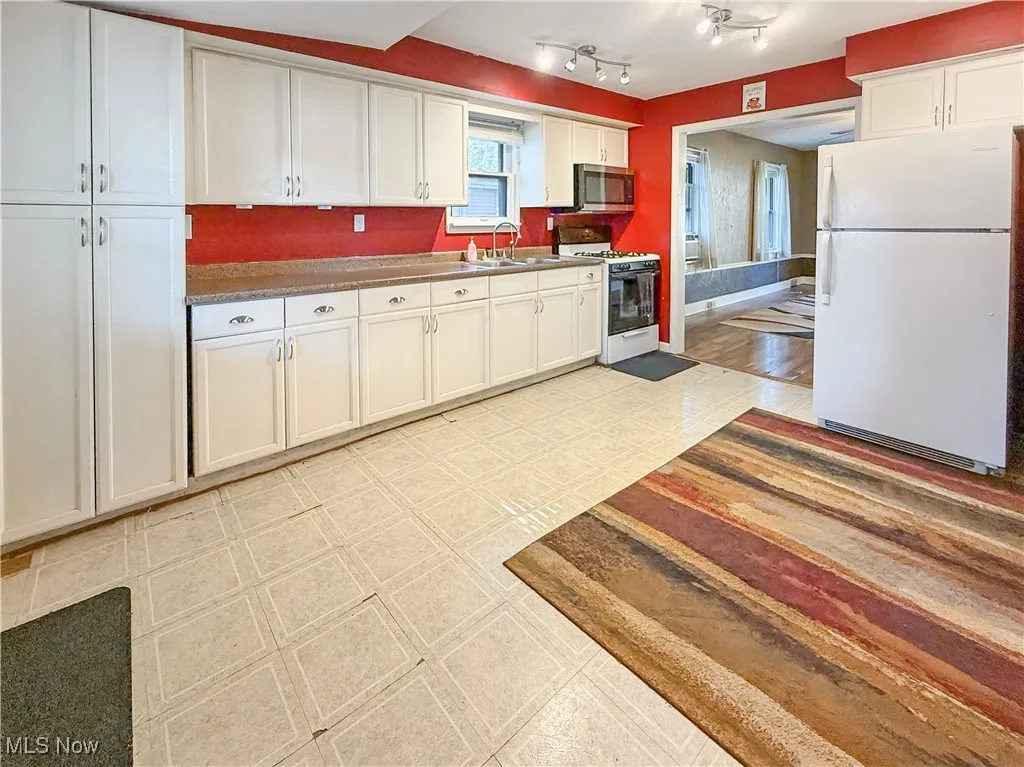 Kitchen featuring white appliances, light floors, and white cabinetry