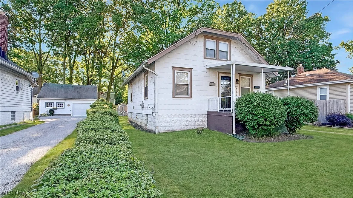 View of front of house with an outdoor structure, a detached garage, and a front lawn