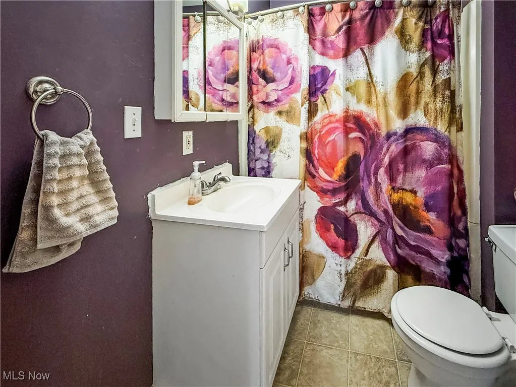 Bathroom with vanity, light tile patterned floors, and curtained shower