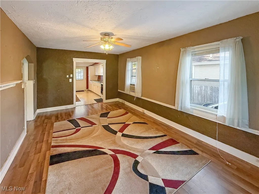 Empty room with light wood-style flooring, a ceiling fan, and a textured ceiling