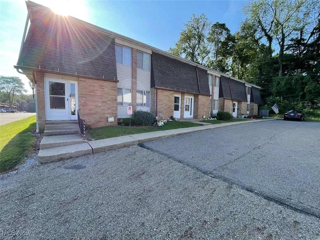 View of front of property featuring roof with shingles, brick siding, and mansard roof
