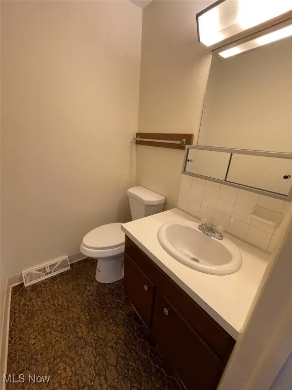 Half bathroom featuring vanity and backsplash