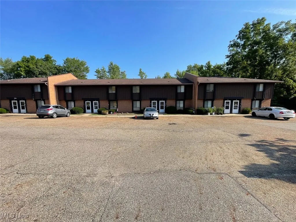 View of front of property featuring brick siding, uncovered parking, and french doors
