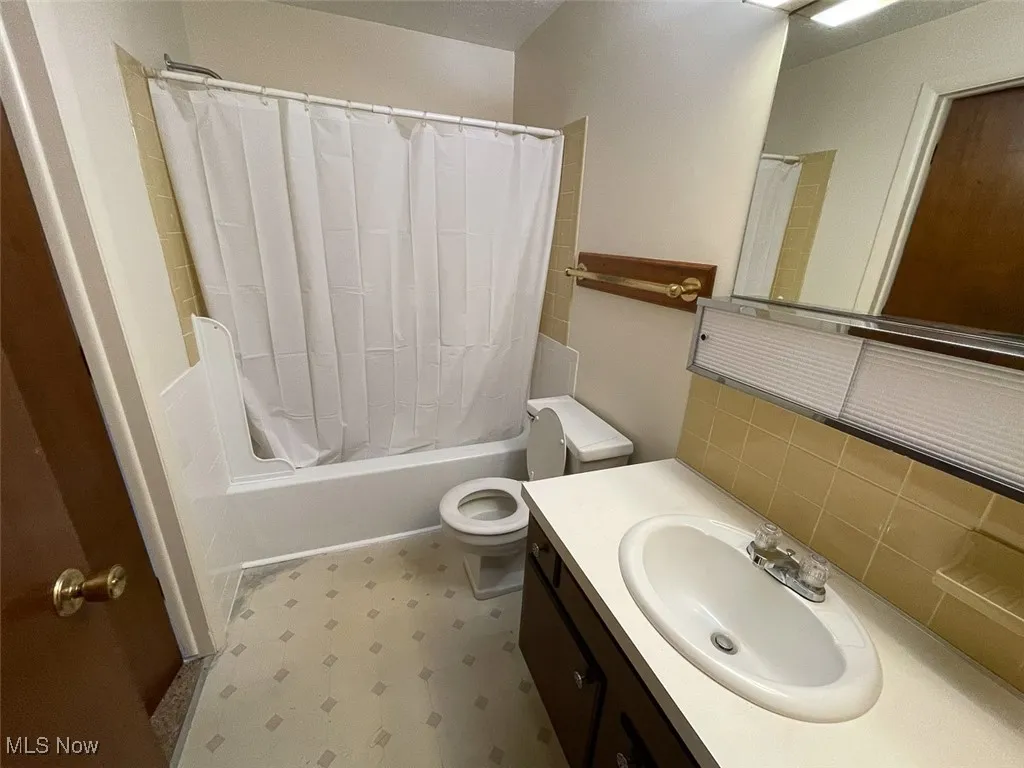 Full bath with shower / bath combination with curtain, vanity, and light floors