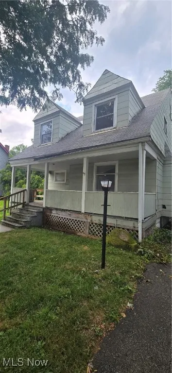 View of home's exterior featuring roof with shingles, covered porch, and a yard