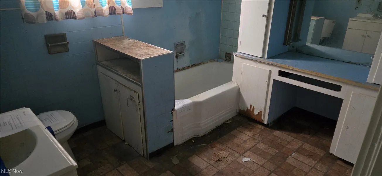 Bathroom featuring a bath, brick patterned flooring, and vanity