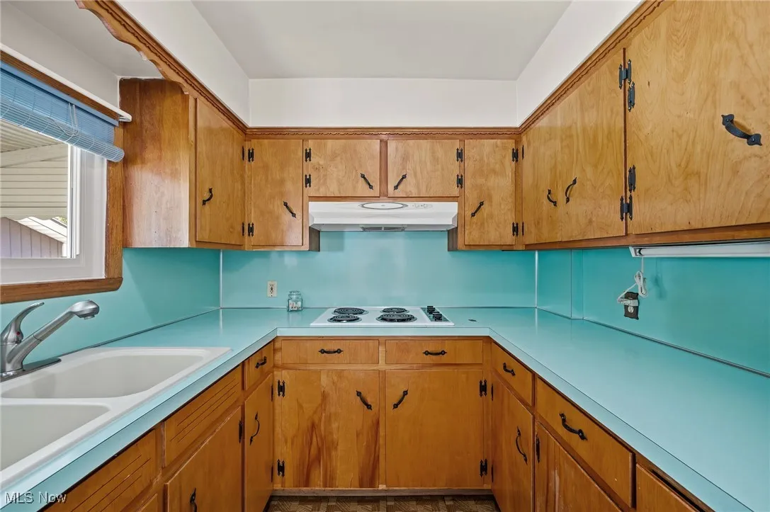 Kitchen featuring light countertops, brown cabinetry, and under cabinet range hood