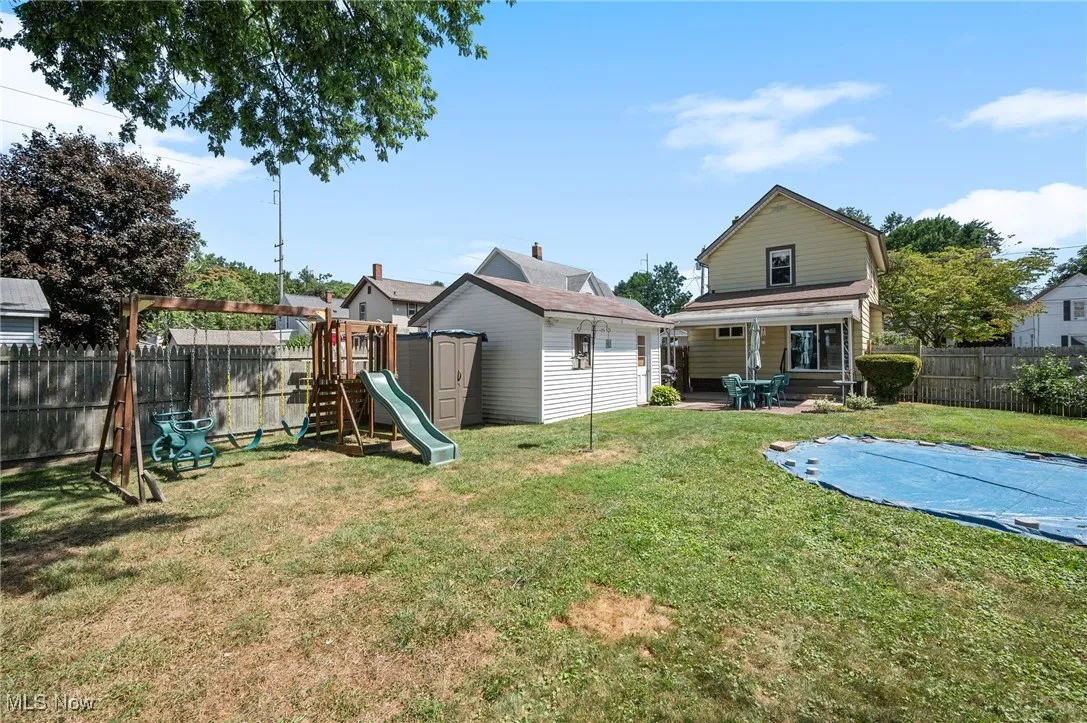 Fenced backyard featuring a playground and a patio area