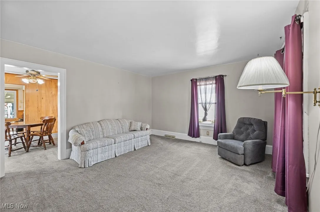 Carpeted living area featuring baseboards and a ceiling fan