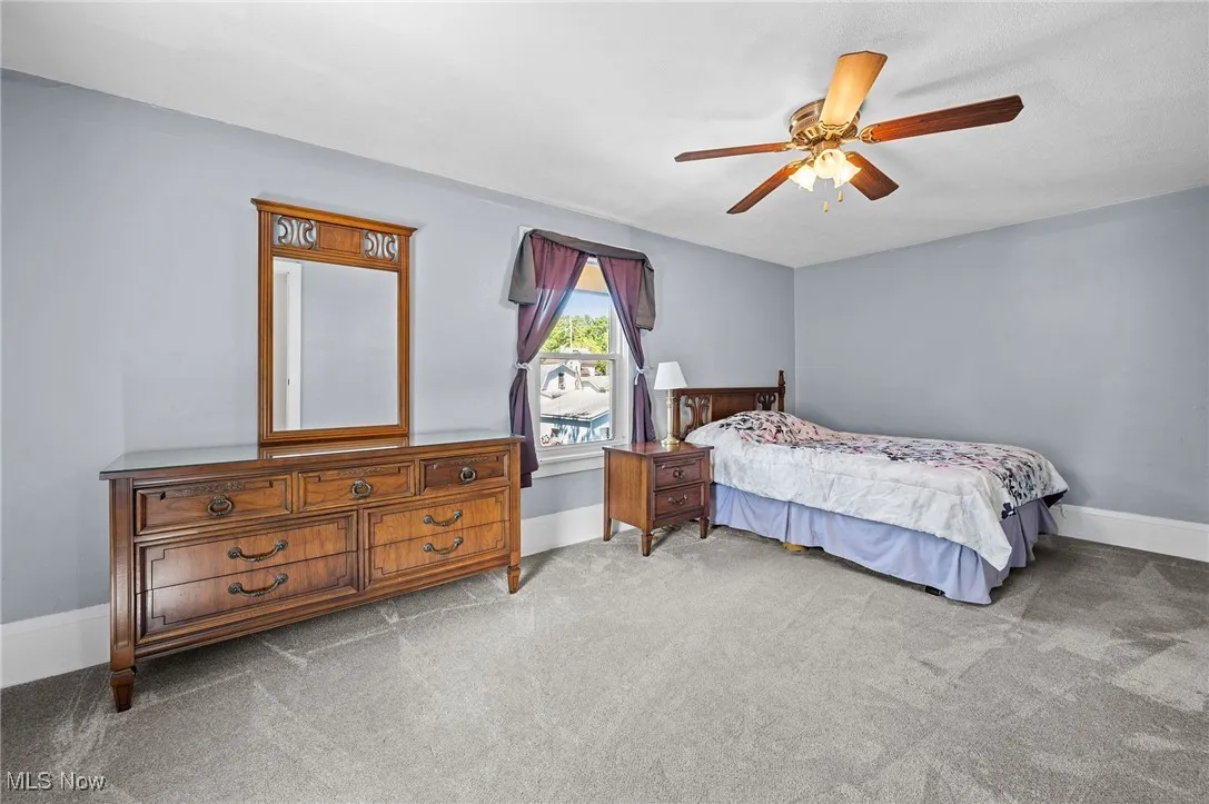 Bedroom with light carpet and a ceiling fan
