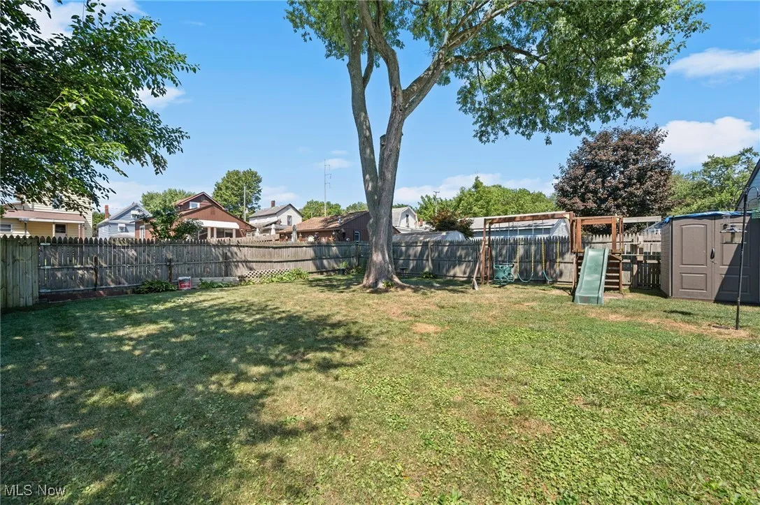Fenced backyard with a storage shed and a residential view
