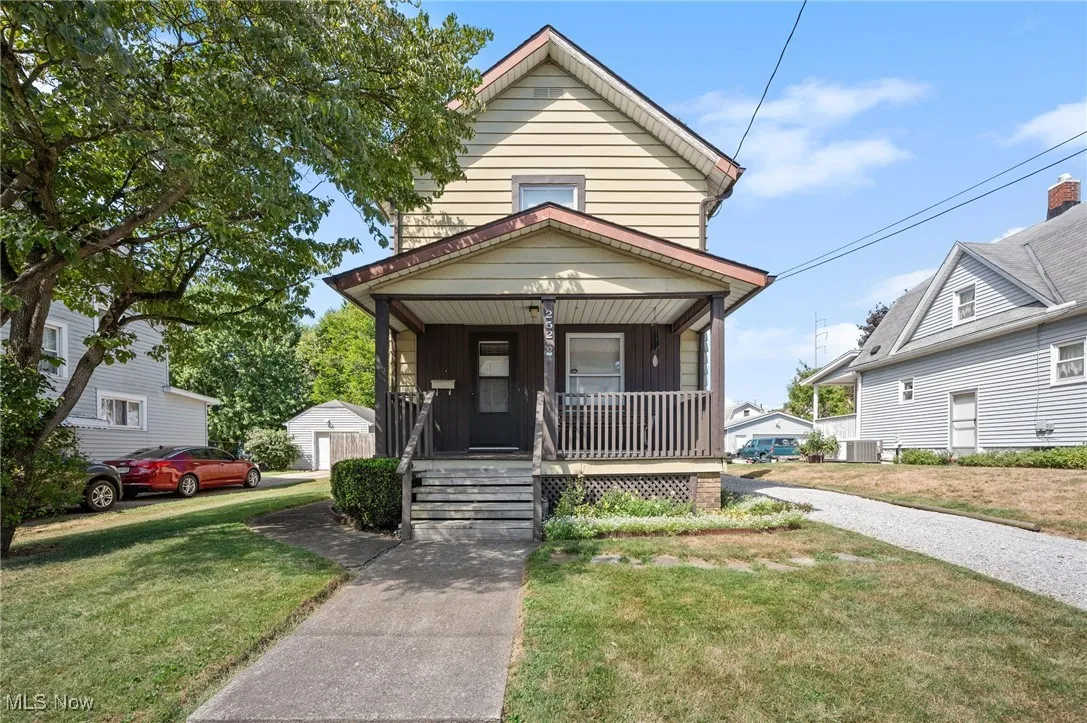 View of front of home featuring covered porch, a front yard, an outbuilding, and a garage