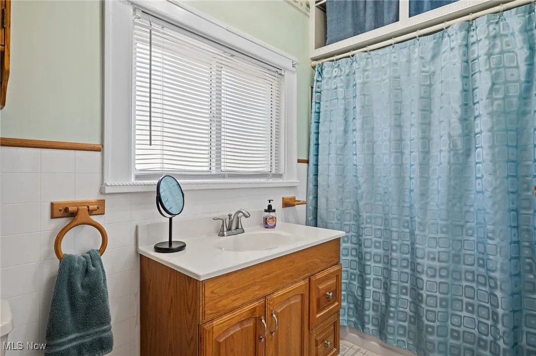 Bathroom featuring vanity, a shower with curtain, and tile walls