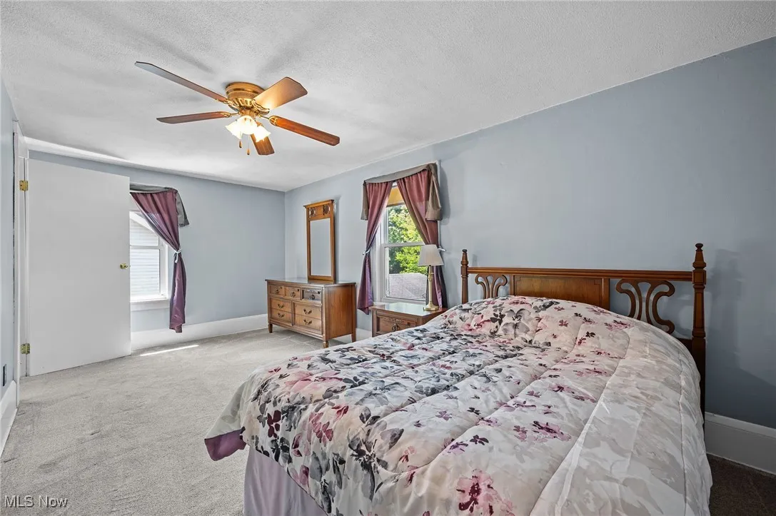 Carpeted bedroom with a ceiling fan and a textured ceiling