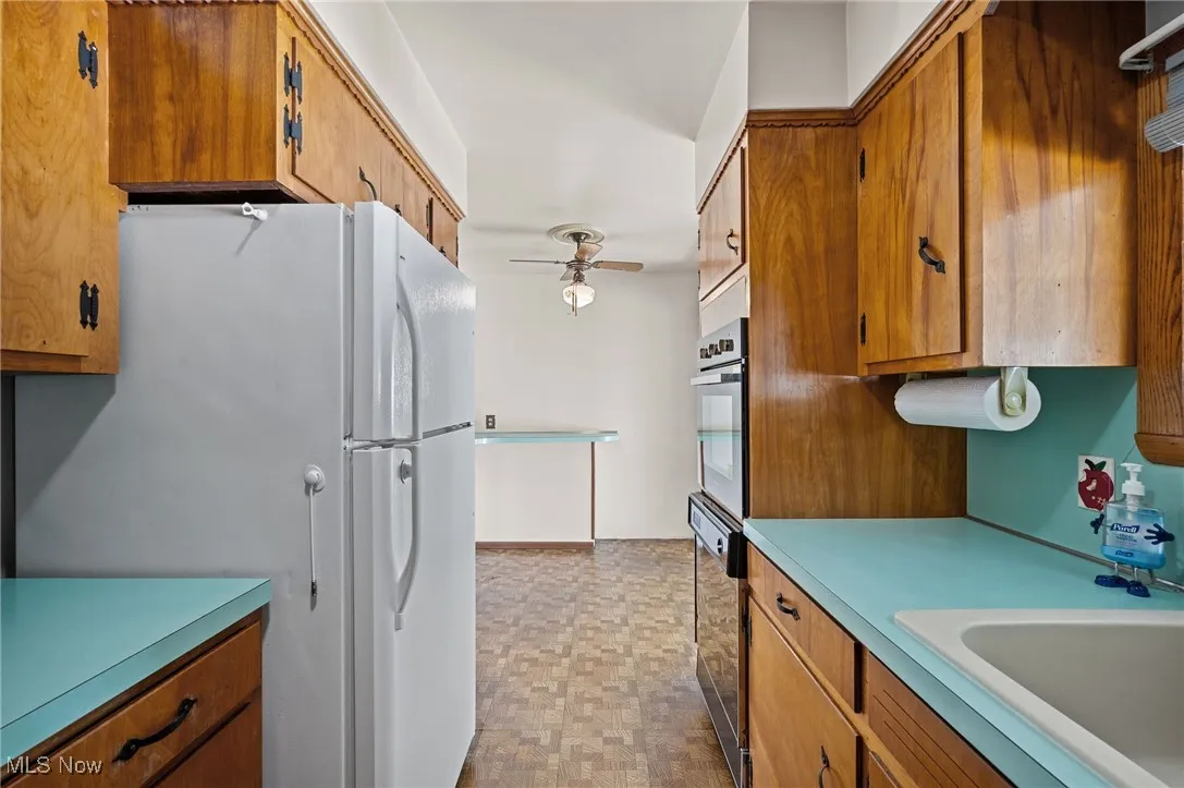 Kitchen with brown cabinetry, freestanding refrigerator, and light countertops