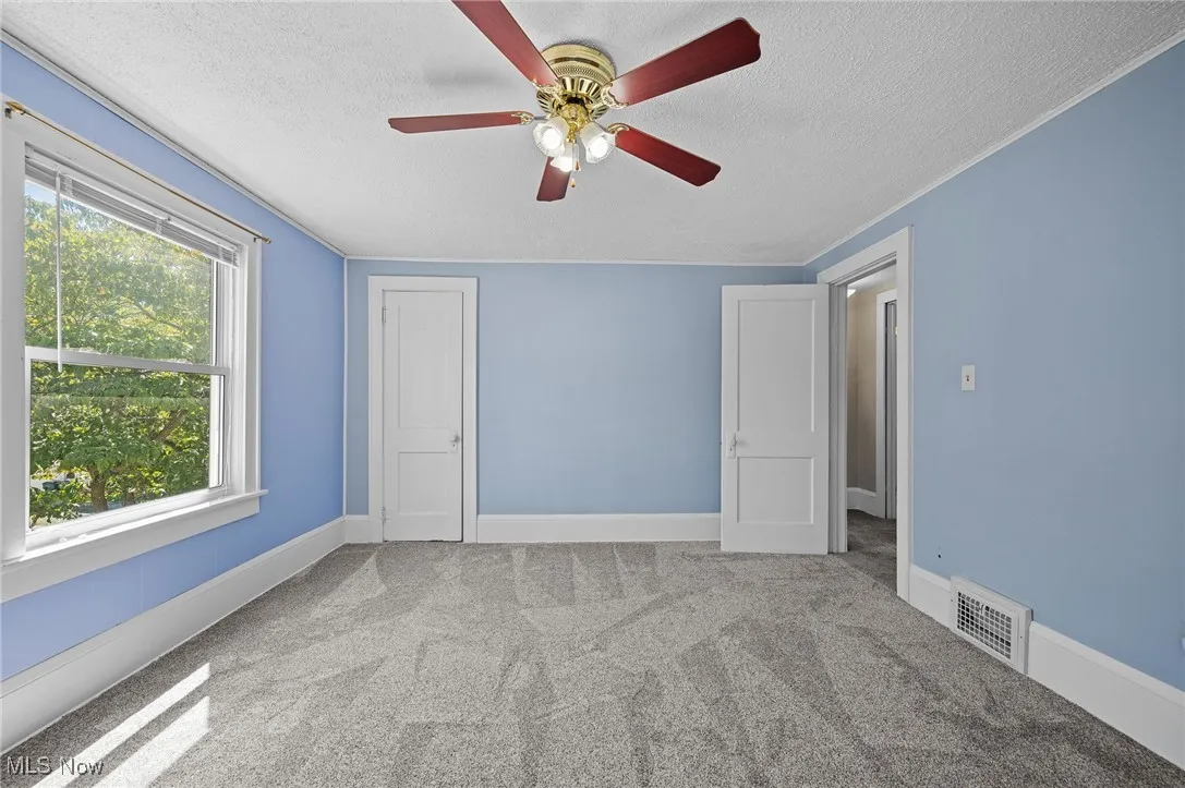 Carpeted empty room featuring a textured ceiling and ceiling fan