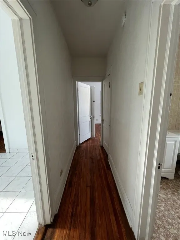 Corridor featuring baseboards and dark wood-style flooring