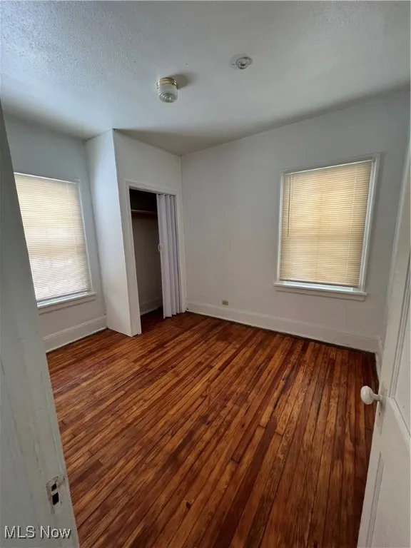 Unfurnished bedroom featuring a textured ceiling, hardwood / wood-style floors, and a closet