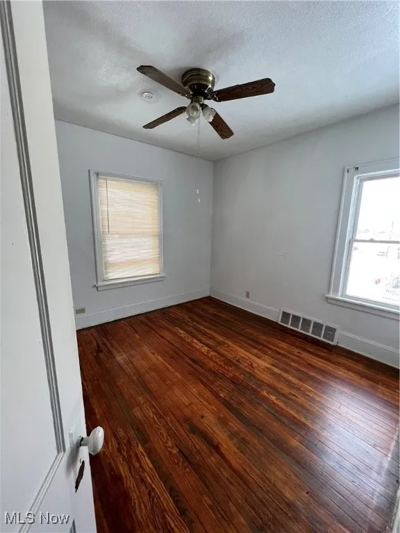 Unfurnished room featuring dark wood-style floors, a textured ceiling, and a ceiling fan