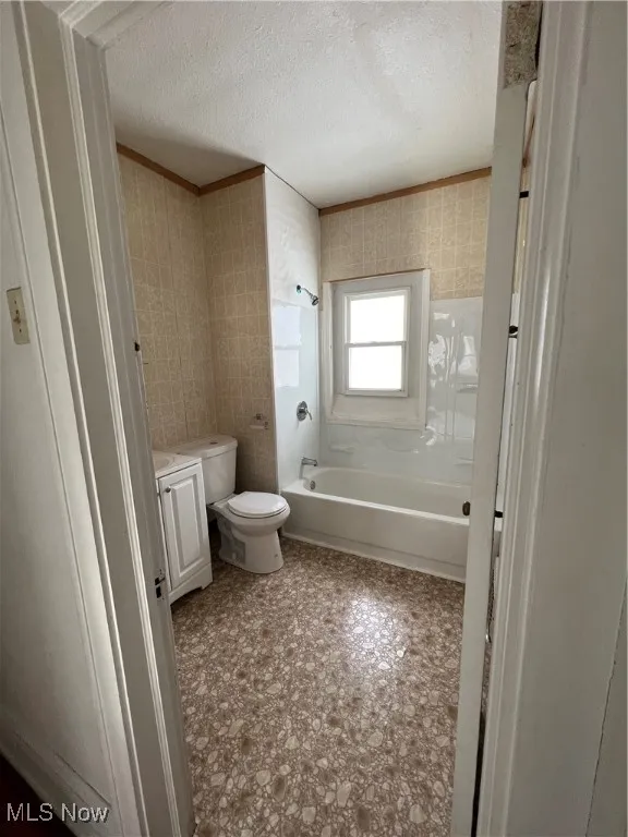 Bathroom with shower / washtub combination, a textured ceiling, vanity, wallpapered walls, and ornamental molding