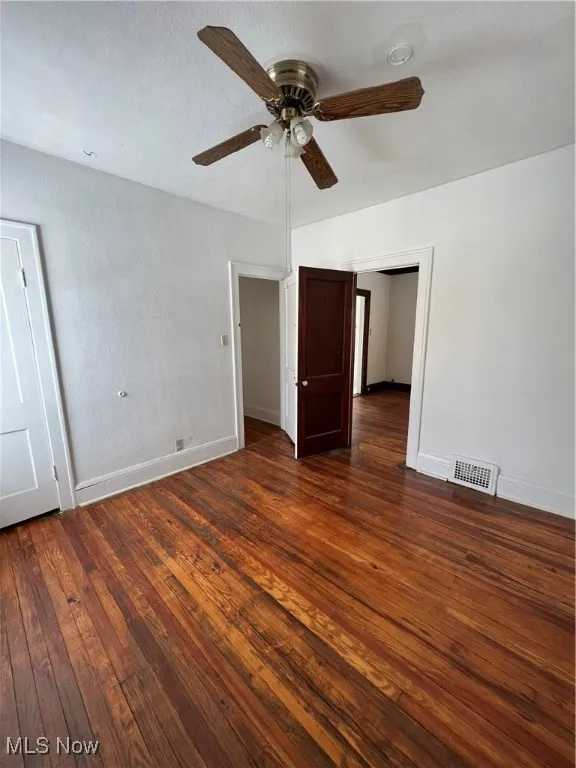 Unfurnished bedroom featuring dark wood-type flooring, ceiling fan, and a textured ceiling