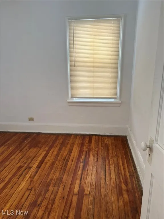 Spare room featuring baseboards and dark wood-style flooring