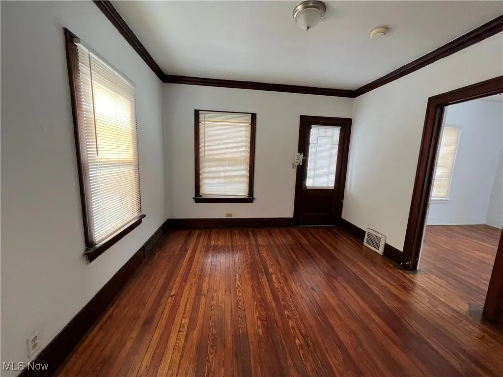 Foyer entrance featuring dark wood-type flooring, crown molding, and healthy amount of natural light