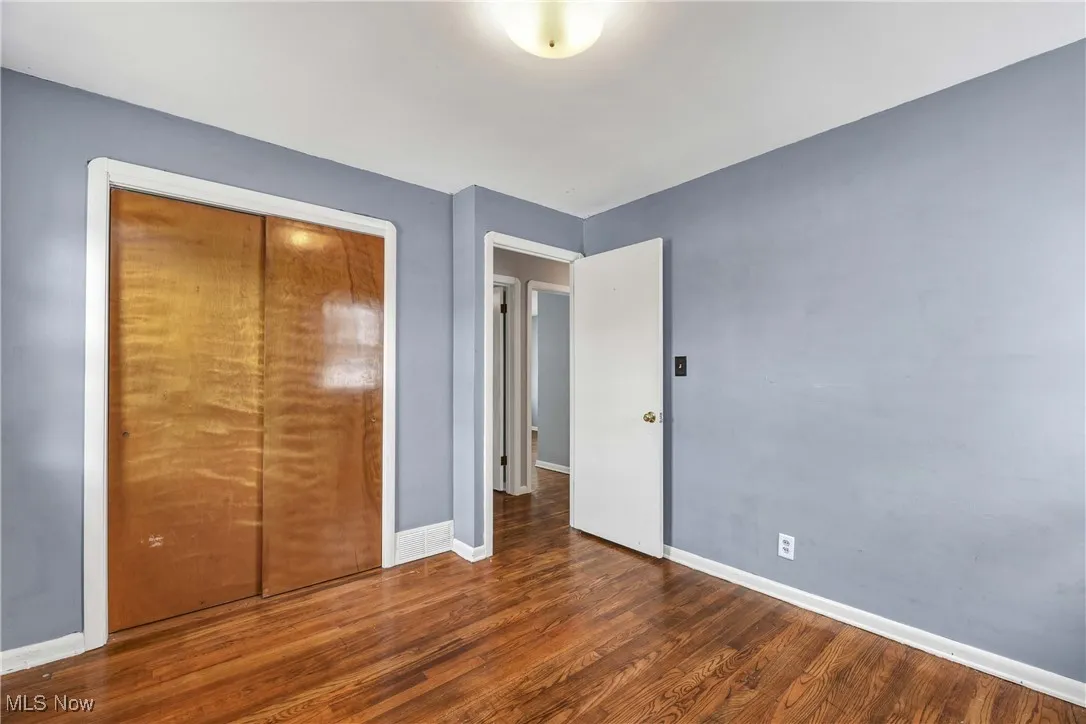 Unfurnished bedroom with dark wood-style floors and a closet