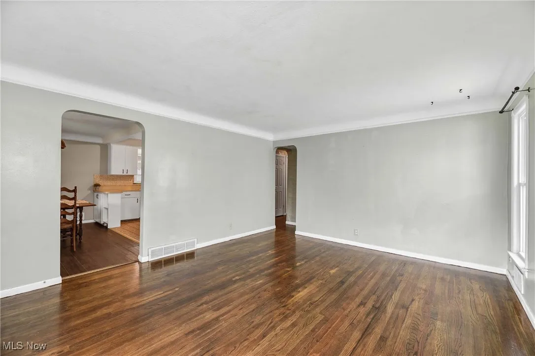 Empty room featuring arched walkways and dark wood-type flooring