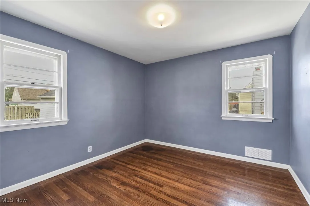 Spare room featuring baseboards and dark wood-type flooring