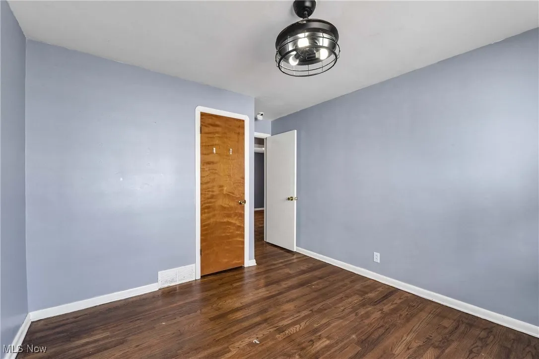 Unfurnished bedroom featuring dark wood-style flooring and baseboards