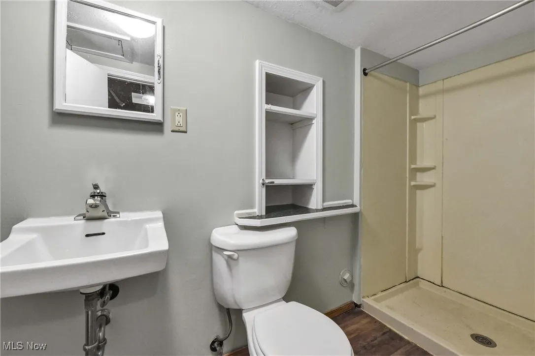 Bathroom with a shower stall and dark wood finished floors