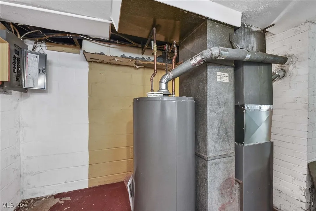 Utility room featuring water heater, electric panel, and heating unit