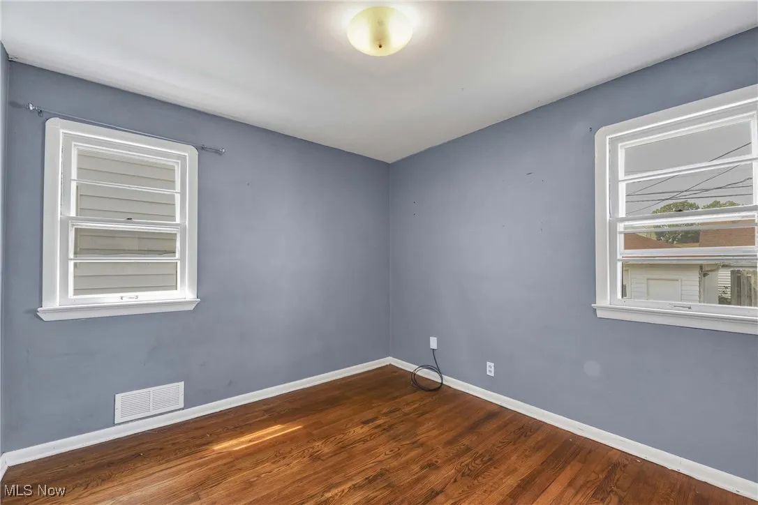 Empty room featuring baseboards and dark wood finished floors