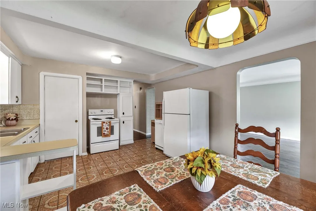 Kitchen featuring white appliances, white cabinetry, light countertops, tasteful backsplash, and arched​​‌​​​​‌​​‌‌​‌‌​​​‌‌​‌​‌​‌​​​‌​​ walkways