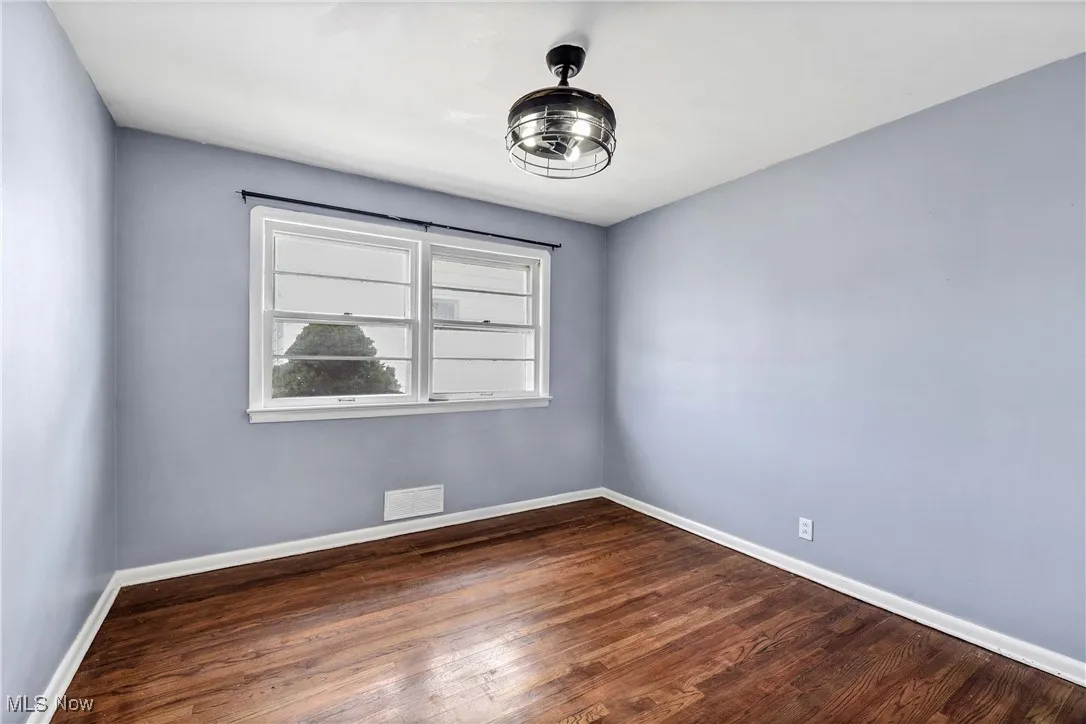 Spare room featuring dark wood-style floors and baseboards