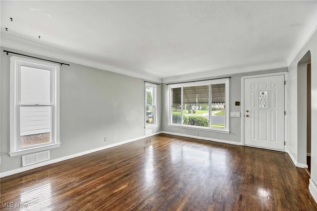 Entryway featuring dark wood-style floors and crown molding
