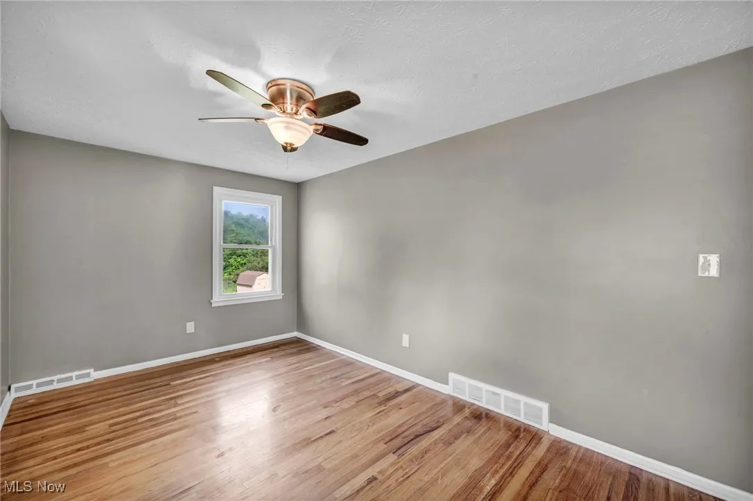 Empty room with light wood-style flooring, a textured ceiling, and ceiling fan