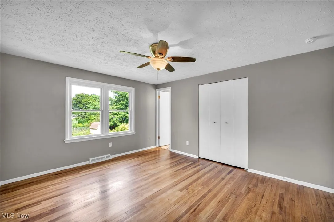Unfurnished bedroom with light wood-style flooring, ceiling fan, a textured ceiling, and a closet