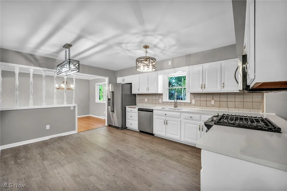 Kitchen featuring a chandelier, pendant lighting, light wood-type flooring, and decorative backsplash