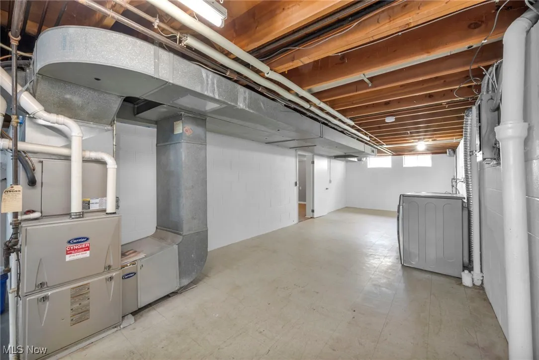 Below grade area with light flooring, washer / dryer, and heating unit