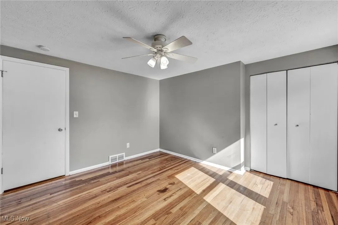 Unfurnished bedroom featuring light wood finished floors, a textured ceiling, ceiling fan, and a closet