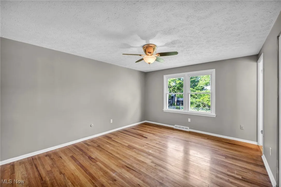 Spare room featuring ceiling fan, wood finished floors, and a textured ceiling