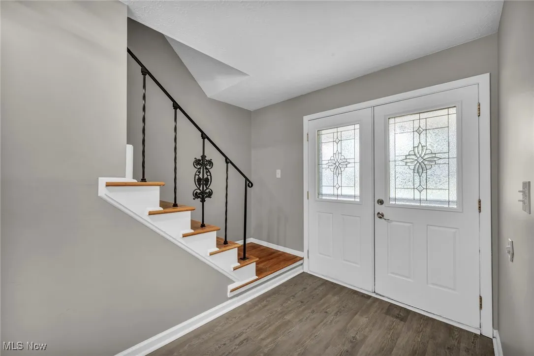 Foyer entrance featuring dark wood-style flooring, stairs, and french doors